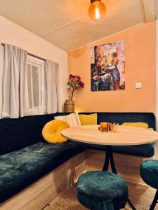 a living room with a table and a couch at Cozy Mobile Home 'Tante Truus' met privé infrarood sauna - Recreatiepark 't Veluwshof - VELUWE in Hoenderloo