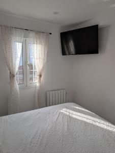 a bedroom with a bed with a television on the wall at Olladas de Laxe Apartamento con vistas in Laxe