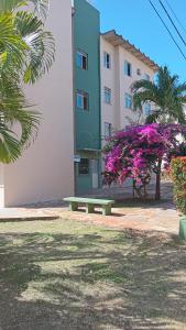 a park bench in front of a building with purple flowers at Apartamento A 700m da orla mais bonita do país no bairro Atalaia in Santa Maria