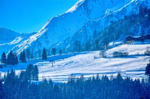 a snow covered hill with a house and a mountain at Select Apartment TOP 8 Kaprun Fürth by Jara in Piesendorf