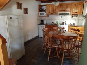 a kitchen with a table and chairs and a refrigerator at Cabañas frente al lago, lugar soñado in San Martín de los Andes