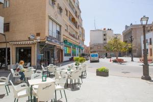 an empty sidewalk with tables and chairs on a city street at Pensión Juan Pedro in Roquetas de Mar