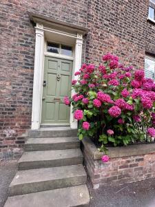 a green door with pink flowers in front of a brick building at Bishy Hill Town House in York in York