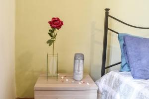 a rose in a vase on a table next to a bed at La Corte Segreta - Dimora nel cuore di Urbino in Urbino