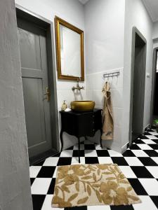 a bathroom with a sink and a black and white checkered floor at JUCIN apartman in Zrenjanin
