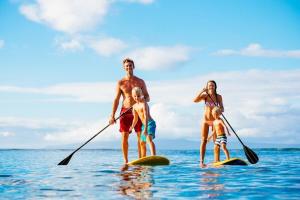 a man and a woman and a child on paddle boards in the water at Kaleialoha 401 · KA 401 Spacious Studio w Mountain View Pool AC in Kahana