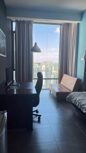 a bedroom with a desk and a bed and a window at Comfy Empire Damansara Studio in Petaling Jaya +3 photos