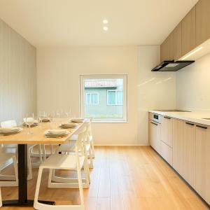 a kitchen with a wooden table and white chairs at The Lobs Toya, Chalet Secca in Lake Toya