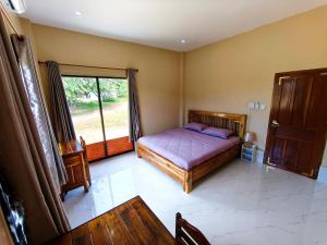 Schlafzimmer mit einem Bett, einem Fenster und einem Tisch in der Unterkunft Vang Vieng Cozy Villa in Vang Vieng