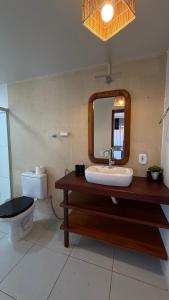 Un baño con lavabo, inodoro y espejo. en Pousada O Portuga, en São Miguel dos Milagres