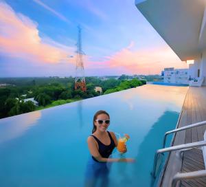 una mujer en una piscina con una bebida en Grand River View Hotel - Rajshahi, en Rājshāhi