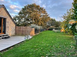 a backyard with a wooden deck and a grass yard at Gîtes d Izel2 entre terre et mer prés d'un golf in Ploemel