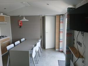 une salle à manger avec une grande table et des chaises blanches dans l'établissement mobil home 4 personne, à Houlgate
