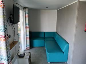 un canapé bleu dans une pièce avec une fenêtre dans l'établissement mobil home 4 personne, à Houlgate