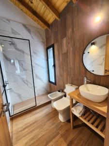 ein Badezimmer mit Toilette, Waschbecken und Spiegel in der Unterkunft Wenuk Patagonia in San Carlos de Bariloche + 88 Fotos