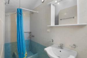 baño con cortina de ducha azul y lavamanos en Anthoula's Sea View Apartment, en Piso Livadi 25 fotos más