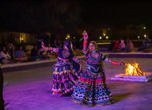 two girls are dancing in front of a fire at Jaipur Eco Village in Jaipur