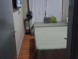a room with two beds and a window with a fan at Neptuno VI in Mar del Plata +13 photos