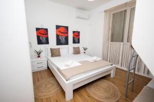 ein weißes Schlafzimmer mit einem Bett und zwei Gemälden an der Wand in der Unterkunft PrivatHomeUlcinj1 in Ulcinj
