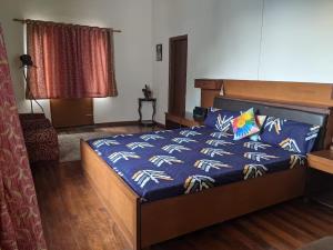 a bedroom with a bed with a blue comforter at HillNesst -Private 3-Bedroom Mountain Home in Bhowali in Bhowāli