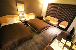 a hotel room with two beds and a chair at Rembrandt Hotel Oita in Oita