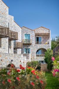 un antiguo edificio de piedra con balcones y flores en Thirides Beach Resort, en Gythio