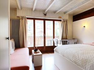 a bedroom with two beds and a large window at Chez Cle'Montagne in Ovronnaz