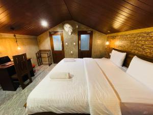 een groot wit bed in een kamer met een stenen muur bij Alice House Hiriketiya in Dikwella