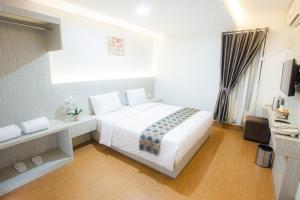 a bedroom with a large white bed and a window at parade inn kendari in Pipulu
