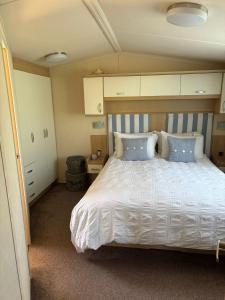 a bedroom with a large white bed with blue pillows at Caravan by Sea in Morfa Nefyn +8 photos