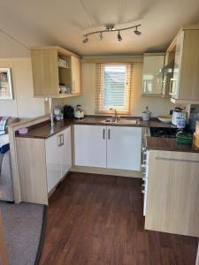 a kitchen with white cabinets and a wooden floor at Caravan by Sea in Morfa Nefyn