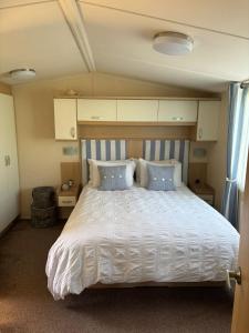 a bedroom with a large white bed with blue pillows at Caravan by Sea in Morfa Nefyn