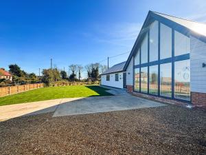 a white building with large windows next to a field at Seafields in Sidestrand