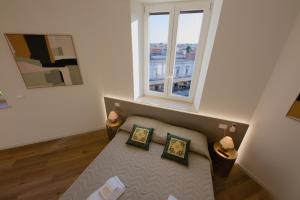 a room with a couch with two pillows and a window at Camera Berlino - La Casa di Carta Affittacamere in Udine