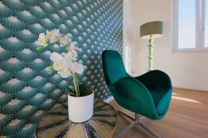 a green chair and a table with a vase of flowers at Camera Berlino - La Casa di Carta Affittacamere in Udine