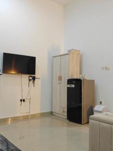 Una habitación con un refrigerador negro y un televisor. en Studio Available in MBZ Abu Dhabi, en Abu Dabi