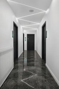 un couloir vide avec des portes noires et des sols en marbre dans l'établissement MONARC Boutique ApartHotel - SELF CHECK-IN, à Iaşi