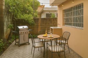 een terras met een tafel, stoelen en een grill bij Relaxing and Serene Guest Room in Cancino