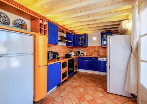 a kitchen with blue cabinets and a white refrigerator at Manu Mykonos Exclusive Villa Luxury Beachside Stay with Private Pool by Quality Brand Villas in Kalafatis