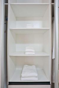 a white closet with two folded towels in it at The Emerald Apartments Ibex Meanwood in Lusaka