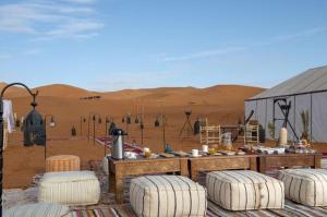 a desert outpost with a table and four stools at Ahlam luxury camp in Merzouga