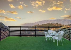 a table and chairs on a balcony with mountains at Holidays Homes Kasauli by Exotic Stays in Kasauli