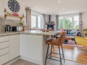 a kitchen with white cabinets and a large clock on the wall at Go Ye Cottage in Leurbost +28 photos