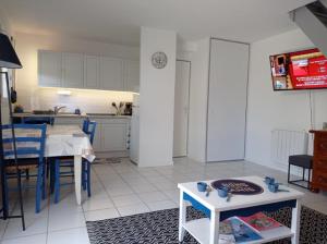 a living room with a table and a kitchen at Charmante Maison Bord de Mer avec Piscine et Tennis 5-P in Saint-Vincent-sur-Jard