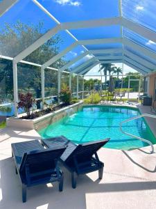 ein Schwimmbecken mit zwei Stühlen und einem blauen Sonnensegel in der Unterkunft Waterfront VILLA with heated Pool&Spa, sunset view, Family&Pets Friendly in Cape Coral