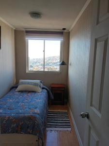 a small bedroom with a bed and a window at Hospedaje en departamento compartido in Valparaíso