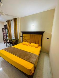 - une chambre avec un grand lit jaune dans l'établissement Great Victoria Palace, à Ratnapura