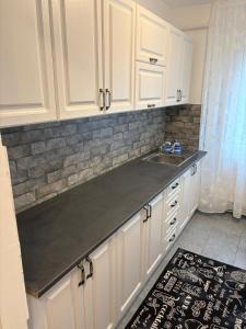 a kitchen with white cabinets and a sink at Apartament Lux 3 camere in Roman