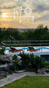two benches sitting next to a swimming pool at Clomplejo MUNAY con piscina y parking in Villa Cura Brochero