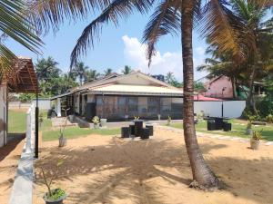 a house with a palm tree in front of it at Samudura Beach House, Owakanda in Rathgama